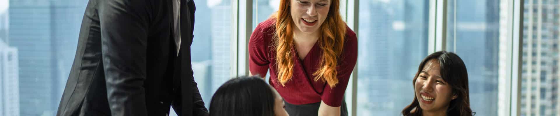 Um grupo diversificado de quatro profissionais em trajes de negócios celebra em um restaurante de luxo com vista para a cidade.