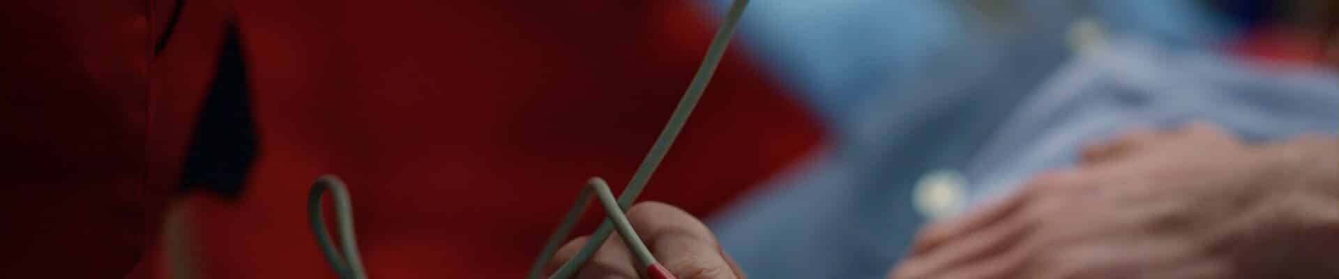 Uma pessoa deitada segura um sensor médico preso ao dedo, usado para monitorar sinais vitais em um ambiente hospitalar.