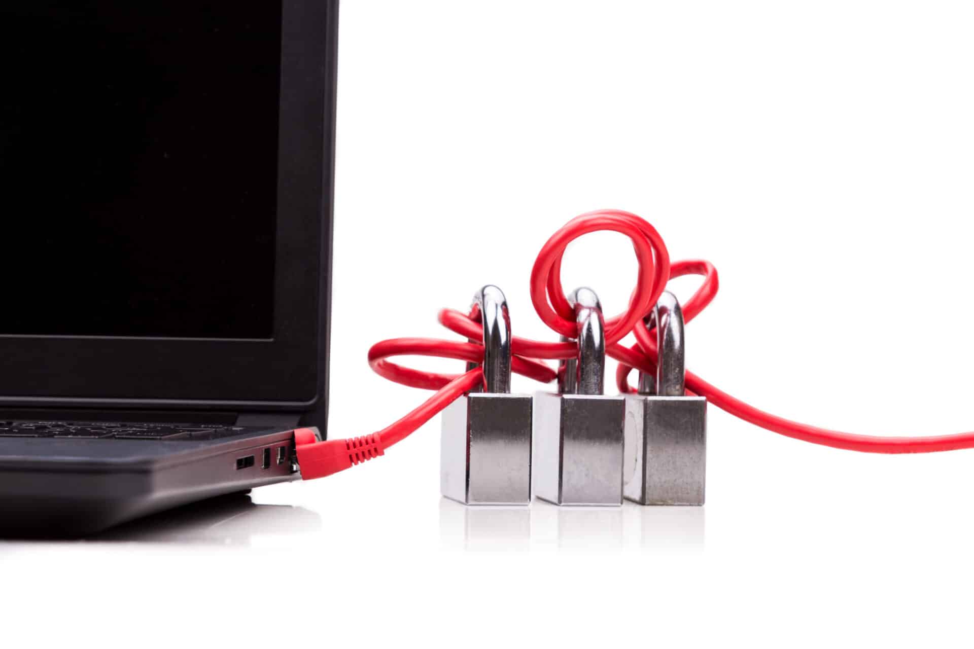 Um cabo de rede vermelho, plugado na lateral de um notebook preto, está emaranhado em volta de três cadeados prateados