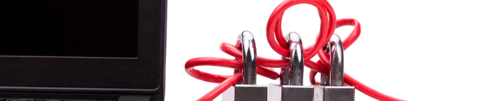 Um cabo de rede vermelho, plugado na lateral de um notebook preto, está emaranhado em volta de três cadeados prateados