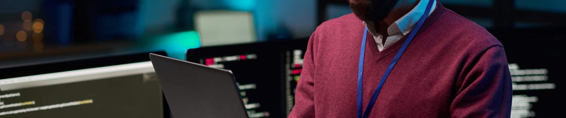 Homem em pé em escritorio com um notebook