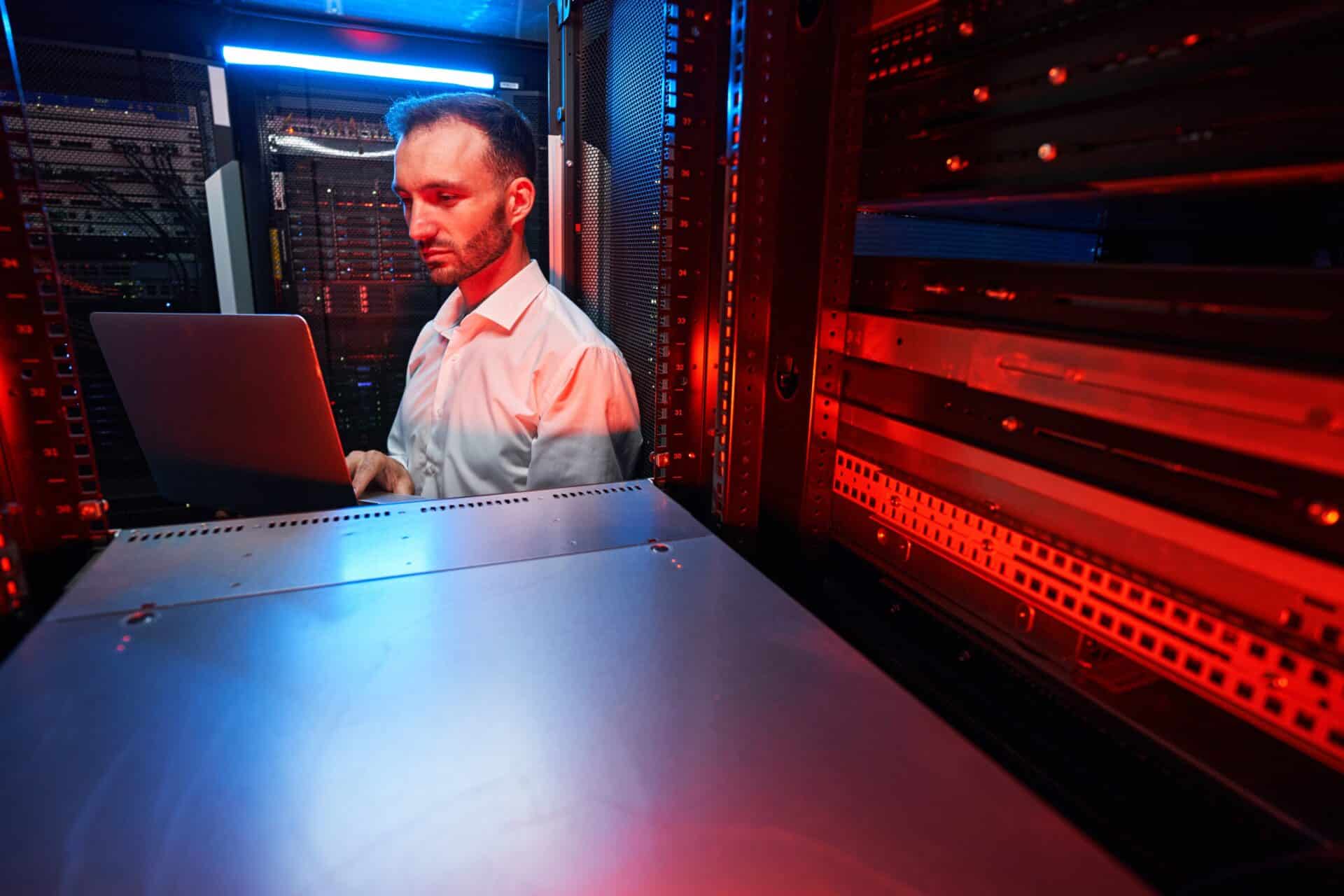 Profissional em TI trabalhando em uma sala cheia de maquinas