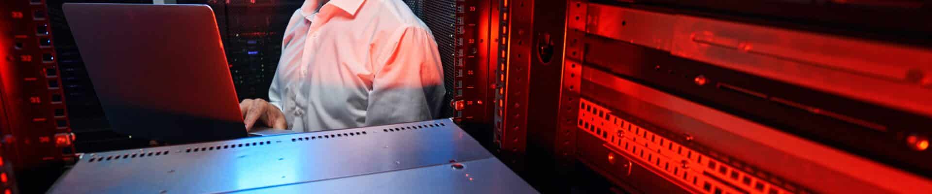 Profissional em TI trabalhando em uma sala cheia de maquinas