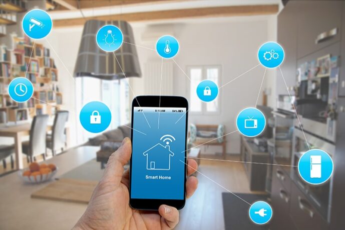 Uma mão segura um smartphone em primeiro plano, exibindo na tela um ícone de casa com sinal de Wi-Fi e a frase "Smart Home". Ao redor do celular, diversos ícones azuis flutuantes estão conectados por linhas finas, representando o controle remoto de dispositivos domésticos como câmeras de segurança, lâmpadas, termostatos, fechaduras, televisores e eletrodomésticos.