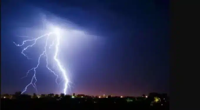 imagem de um céu com um raio forte de chuva sob uma cidade no breu 