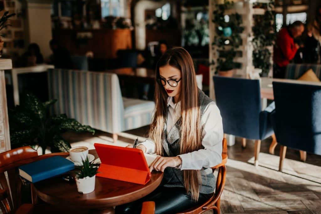 uma mulher trabalhando em modelo remoto, em alguma cafeteria, com o seu notebook