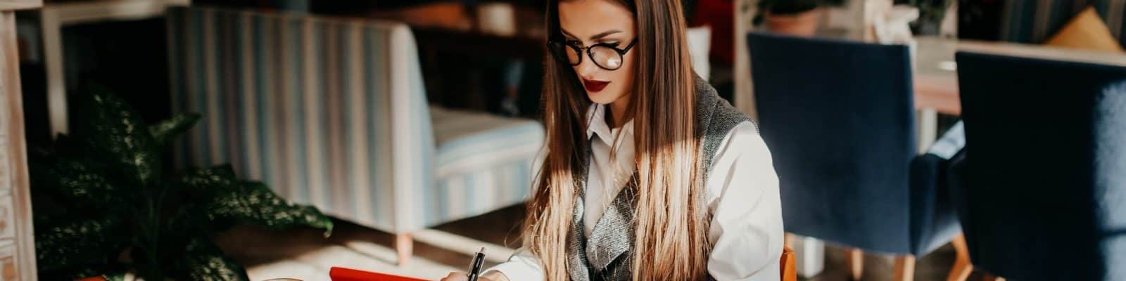 uma mulher trabalhando em modelo remoto, em alguma cafeteria, com o seu notebook