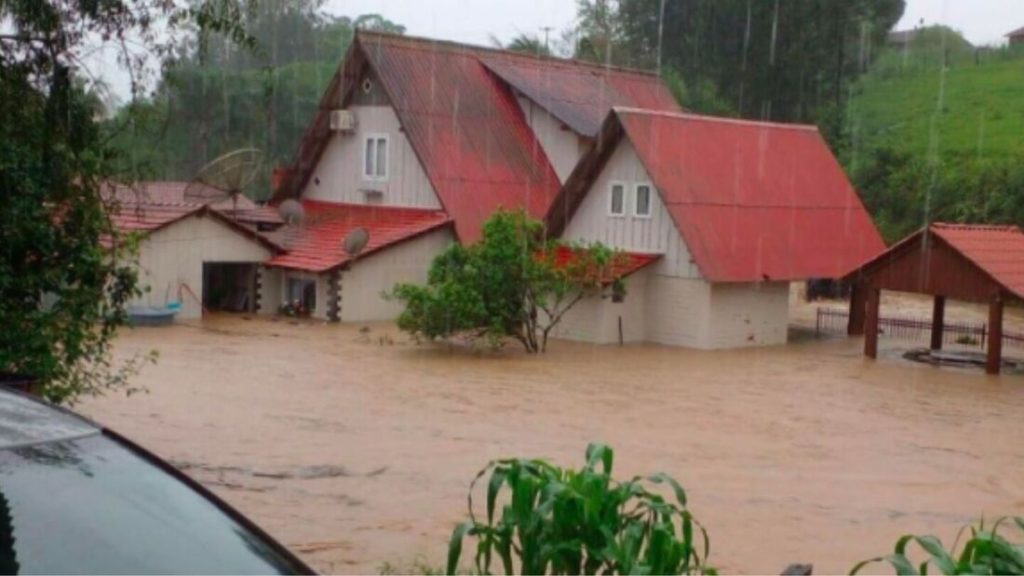 uma imagem de casas quase submersas em uma enchente