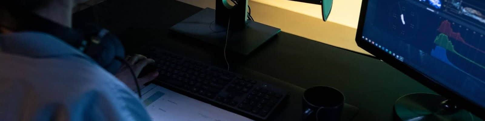 uma pessoa sentada trabalhando com dois monitores de computador