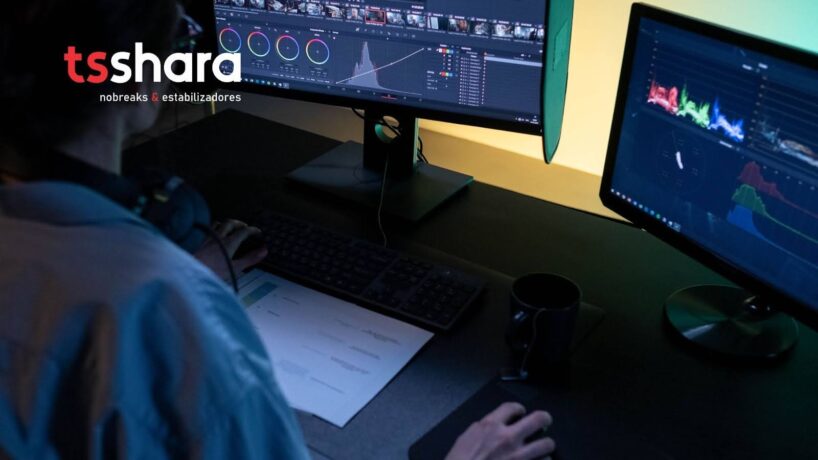 uma pessoa sentada trabalhando com dois monitores de computador