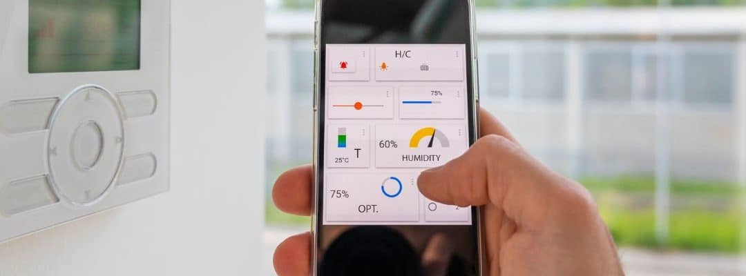 uma imagem de uma mão segurando um celular em frente a um cômodo da casa