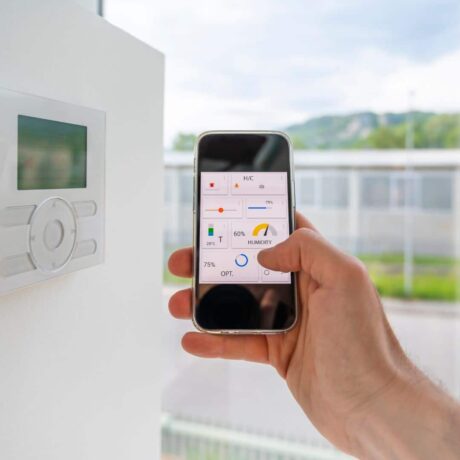 uma imagem de uma mão segurando um celular em frente a um cômodo da casa