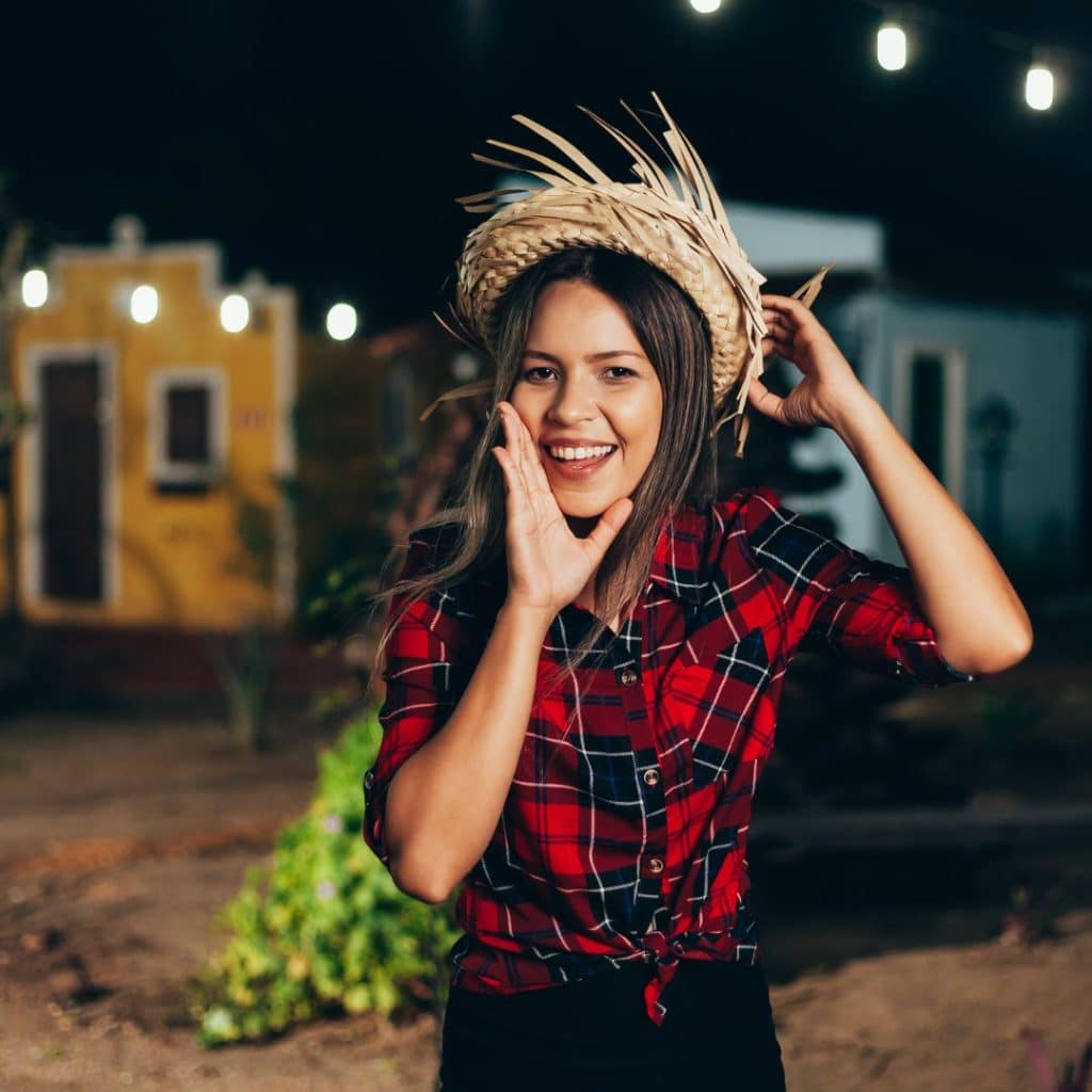 uma jovem com camisa xadrez e chapéu de palha