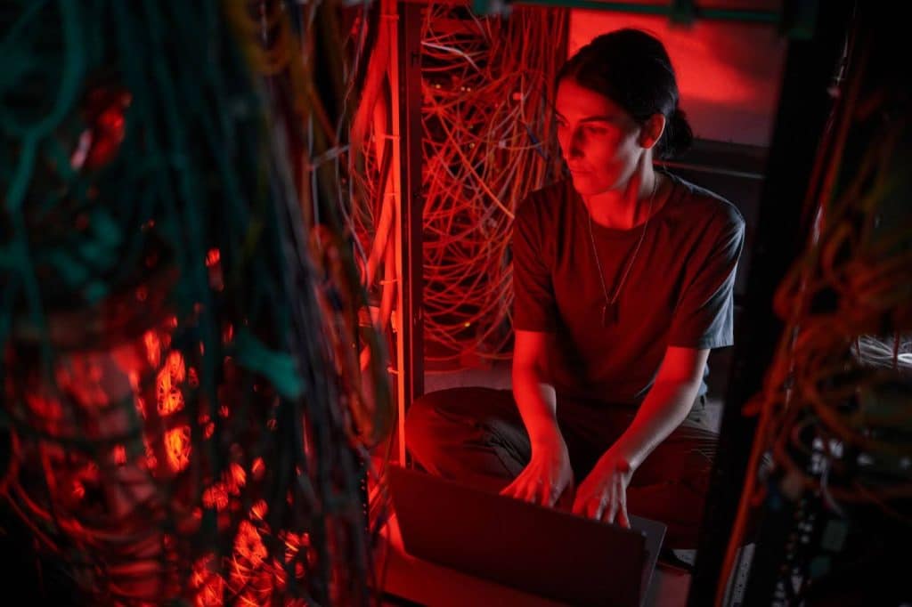 uma mulher em um servidor com notebook e vários cabos a sua volta