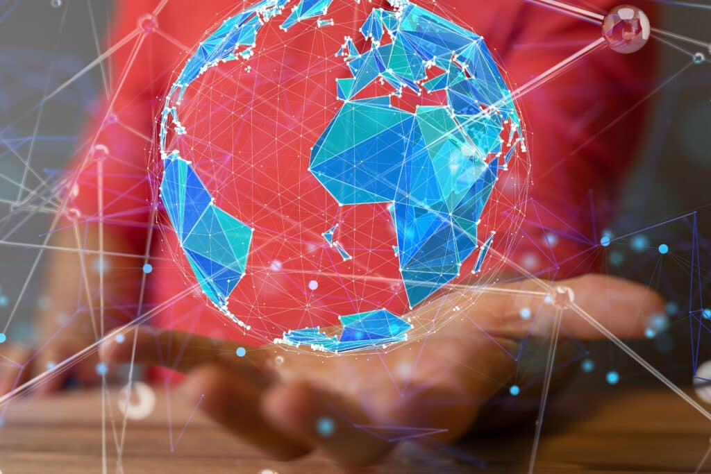 Um holograma digital de um globo terrestre estilizado em tons de azul ciano flutua sobre a mão aberta de uma pessoa.