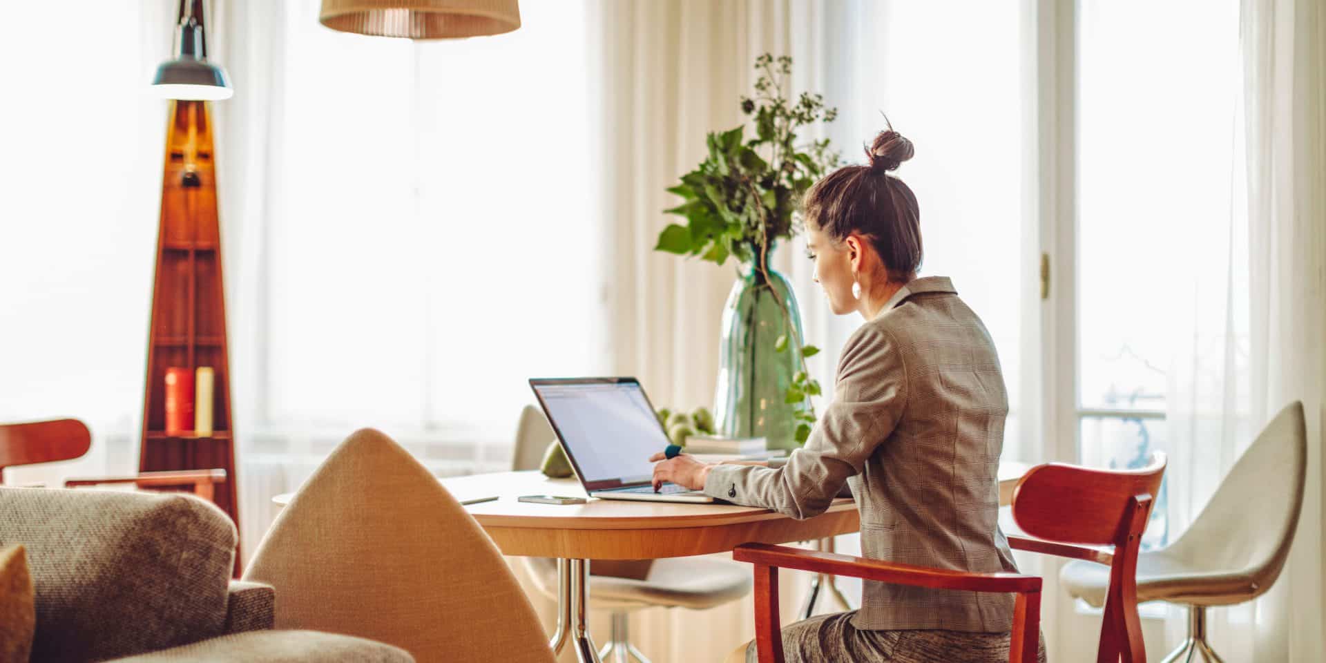 uma mulher sentada na cadeira e sob a mesa um notebook onde ela está trabalhando