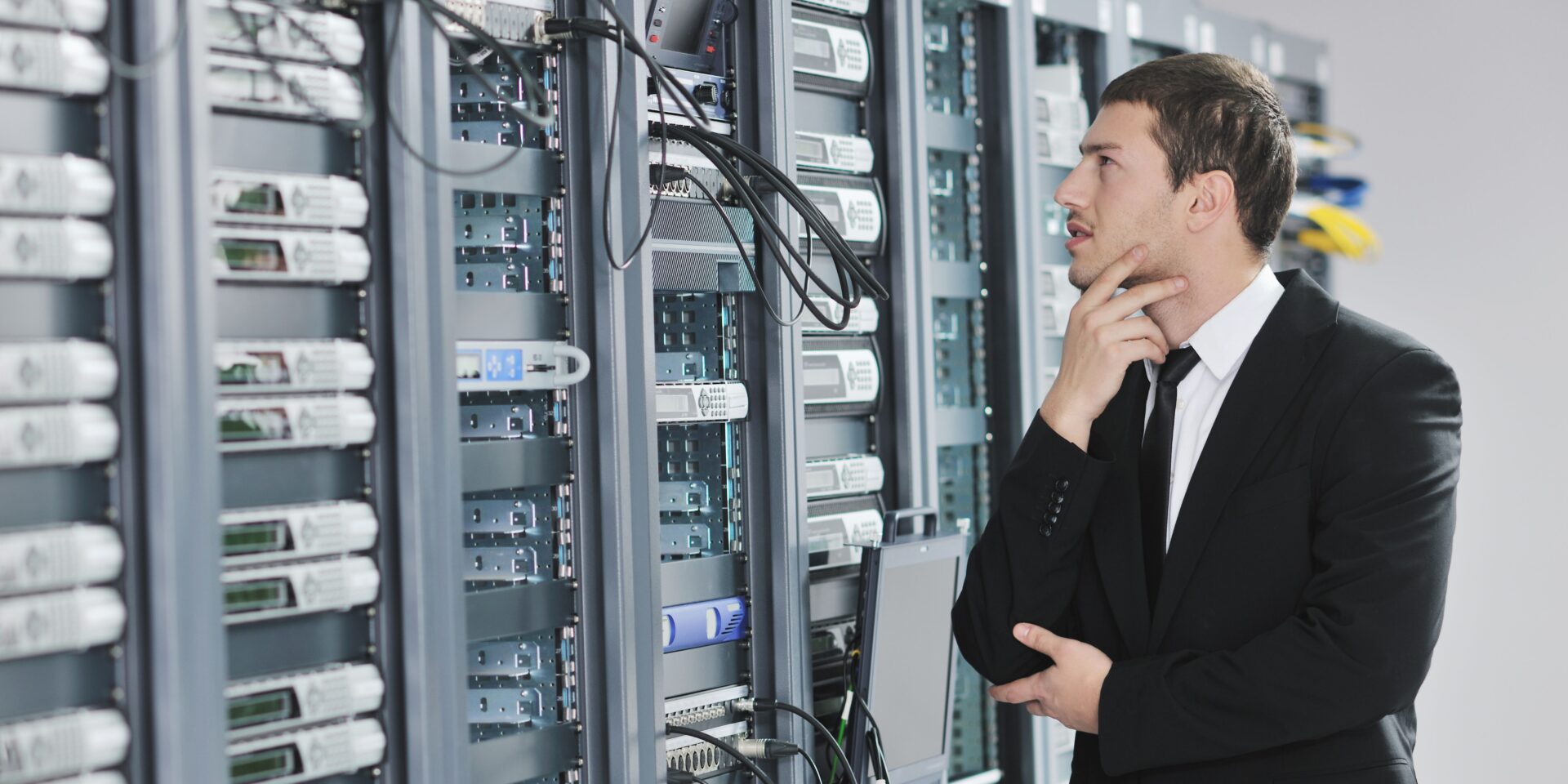 um homem vestido de terno e grsvsts olhsndo para um data center