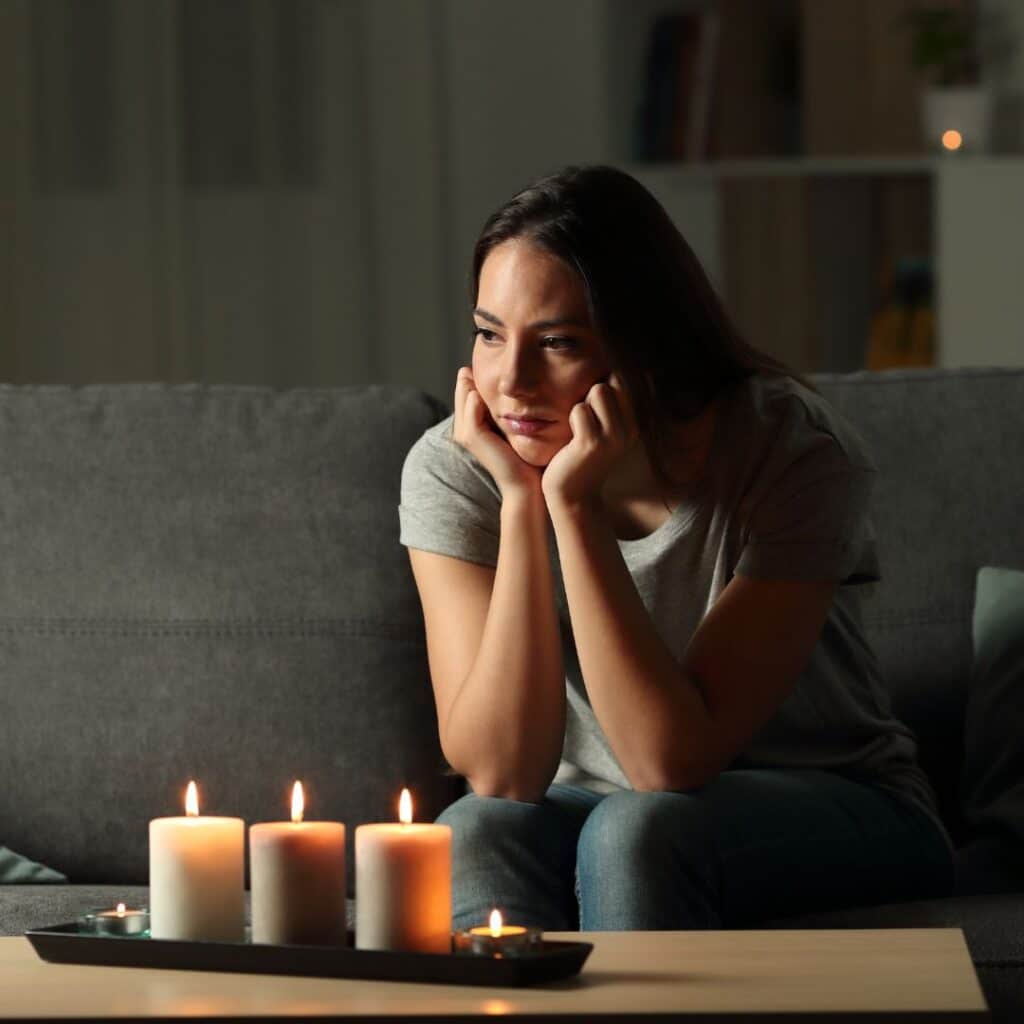 uma mulher sentada sob luz de velas angustiada