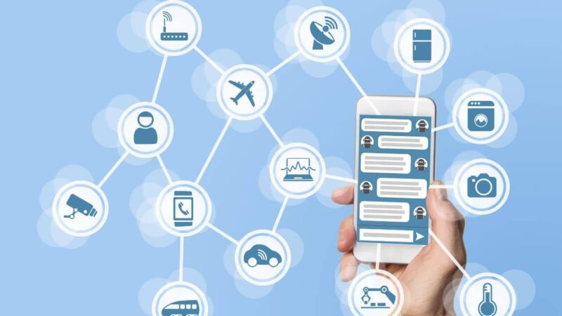 uma mão segurando um smartphone e vários ícones de tecnologia saindo por ele