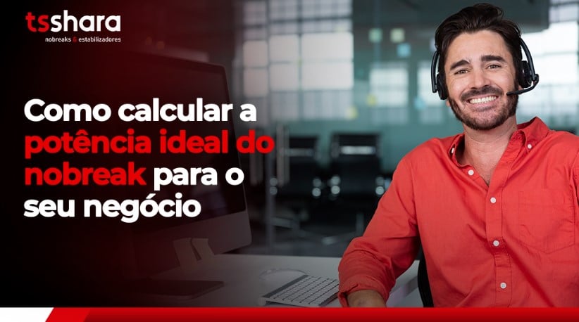 Homem sorridente com headset em frente ao computador em escritório.
