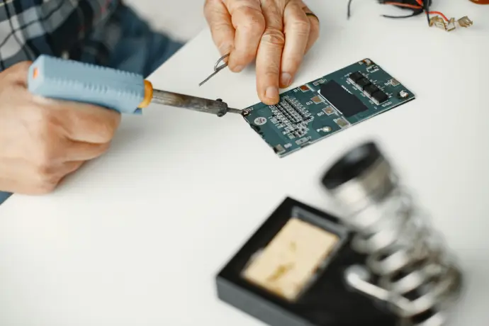 uma mão desparafusando um aparelho eletrônico