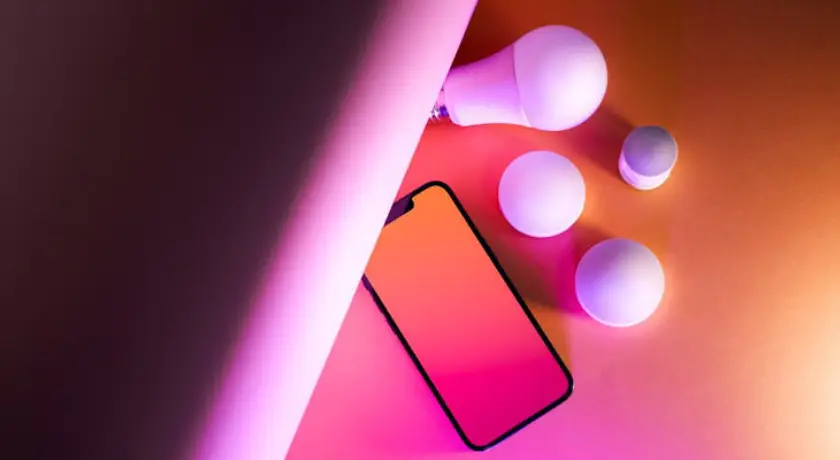 um celular e lampadas de vários formatos em volta dele