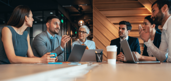 uma sala de escritório com vários colaboradores conversando sobre negócios