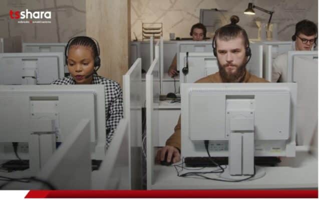 duas pessoas sentadas a frente de computadores