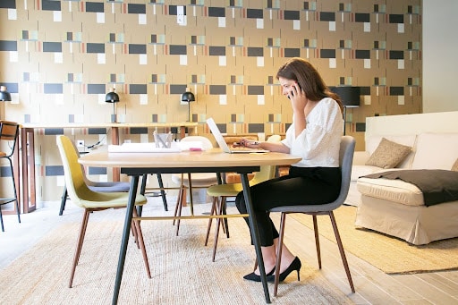 uma mulher sentada na cadeira e mexendo em seu nobreak que está em cima da mesa