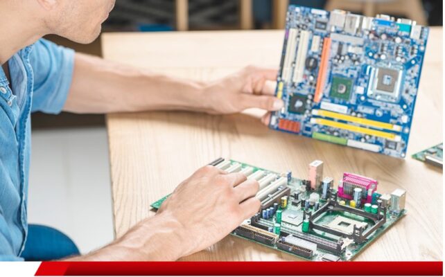 Técnico manuseando placas-mãe de computador sobre mesa.