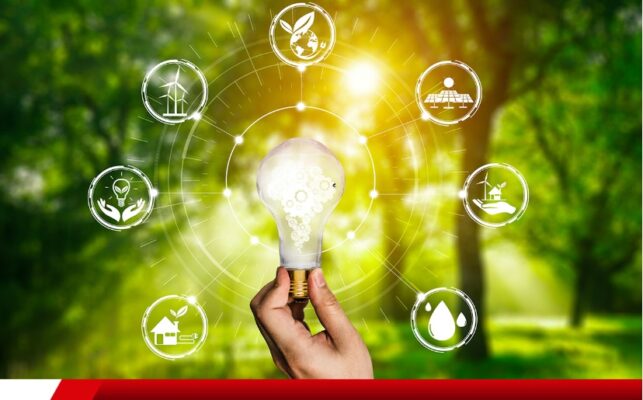 Mão segurando lâmpada com ícones de fontes de energia limpa.