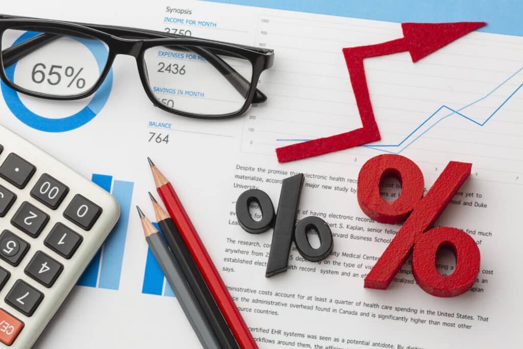 imagem de uma calculadora com um oculos em uma mesa e sinais de porcentagem