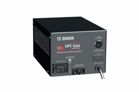 A imagem mostra um nobreak TS Shara modelo UPS Gate Universal. O dispositivo tem uma cor preta e apresenta várias portas e botões na parte frontal. Ele possui tomadas de saída para conectar equipamentos, um botão de liga/desliga (chave), e luzes indicadoras de status. Também é possível ver entradas para conexão de cabos, e o modelo é projetado para fornecer energia ininterrupta, sendo ideal para ambientes que necessitam de proteção elétrica. O design é simples e funcional, com um acabamento metálico.