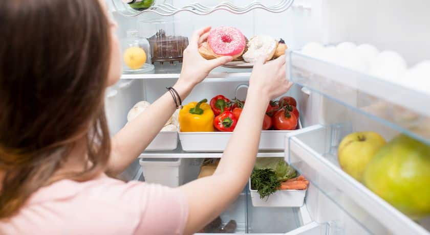 uma mulher pegando alimentos na geladeira