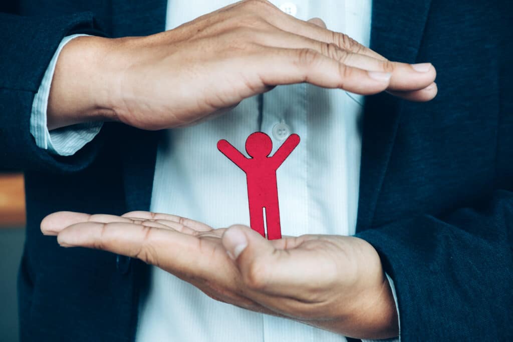 um papel em formato de pessoa na mão de um homem
