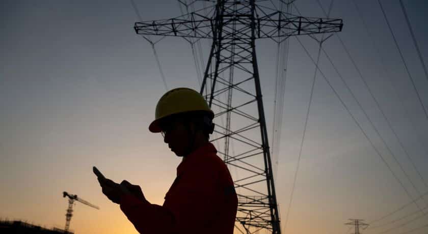 um eletricista perto de uma torre de energia