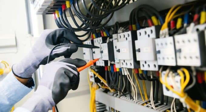 um quadro de energia grande e um eletricista mexendo com pinças