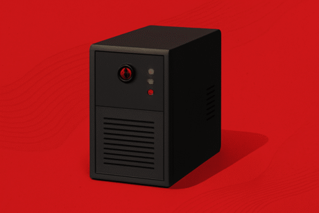 A imagem mostra um gabinete de computador em tom preto fosco sobre um fundo totalmente vermelho. O gabinete tem formato retangular e está posicionado de forma a vermos sua frente e uma das laterais. Na parte frontal, há três pequenos indicadores luminosos alinhados na vertical, em amarelo e vermelho, que lembram luzes de status. Acima deles, há um botão circular preto com um detalhe vermelho no centro, que parece ser o botão de ligar. Abaixo, há uma grade horizontal para ventilação. A lateral visível do gabinete possui pequenas aberturas para circulação de ar. O design é simples, com linhas retas e sem enfeites, transmitindo a ideia de um equipamento robusto e funcional.