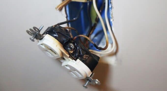 uma tomada caida com os fios expostos e aparencia de queimada 