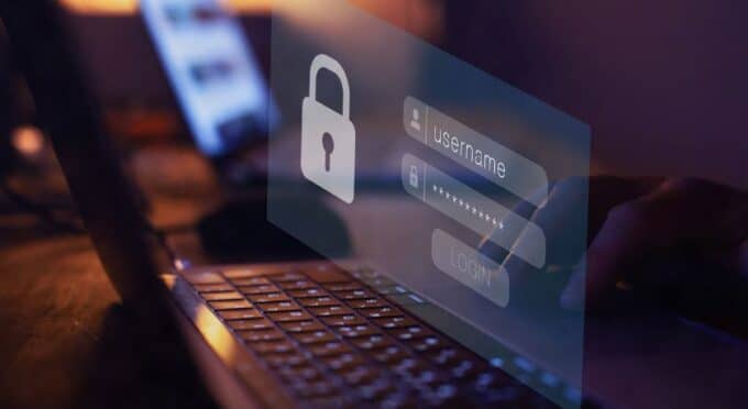Sobreposição digital de uma tela de login de segurança com ícone de cadeado e campos 'username' e 'password', refletida sobre um teclado de laptop