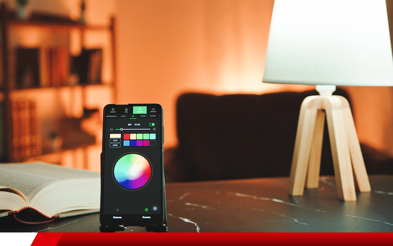 Smartphone controlando lâmpada inteligente com seletor de cores em sala com iluminação quente e ambiente aconchegante.