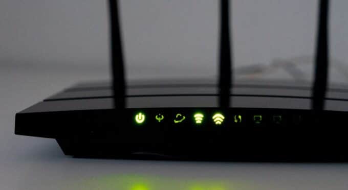 um roteador de internet preto visto de perto com os icones acesos eem luz verde 