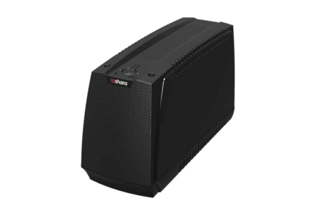 A imagem mostra um nobreak TS Shara com design moderno e compacto. O dispositivo é de cor preta, com uma textura em sua parte frontal, que tem um formato ligeiramente arredondado. Na parte superior, há um botão de controle e indicadores de status, conferindo um visual elegante e funcional, ideal para proteção de dispositivos eletrônicos.