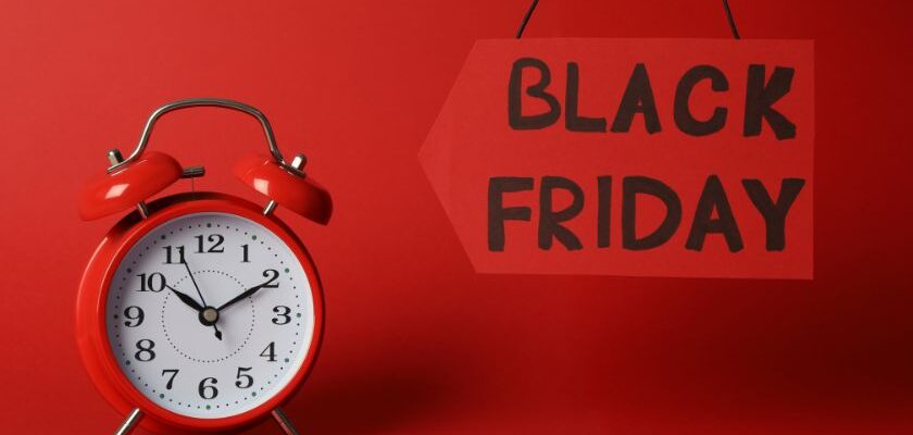 Um relogio vermelho ao lado uma placa escrito ~Black friday~ com o fundo vermelho