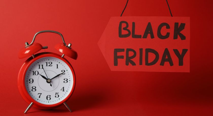 Um relogio vermelho ao lado uma placa escrito ~Black friday~ com o fundo vermelho