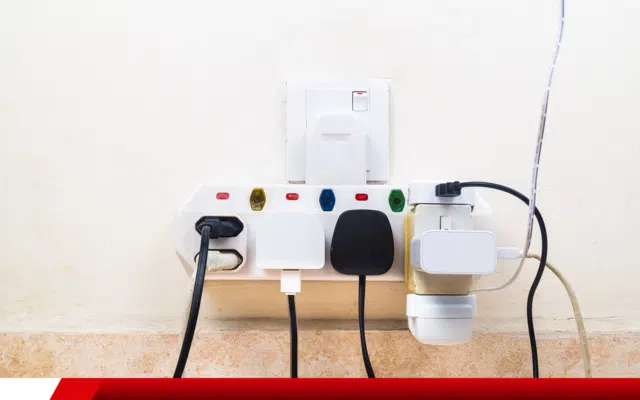 Tomada com múltiplos adaptadores e risco de sobrecarga elétrica.