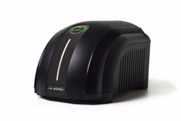 O dispositivo, também fotografado em estúdio com fundo branco, é um modelo preto similar, mas com uma forma mais geométrica, parecendo um cubo com cantos suaves. Sua parte superior é plana e densamente perfurada com pequenos furos de ventilação, e a marca "TS SHARA" está gravada de forma sutil no topo. Um pequeno LED circular de cor verde está aceso próximo ao centro do painel superior. As superfícies frontal e lateral têm uma textura escura, ligeiramente áspera.