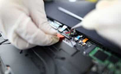 Técnico com luvas realizando manutenção em placa de circuito eletrônico