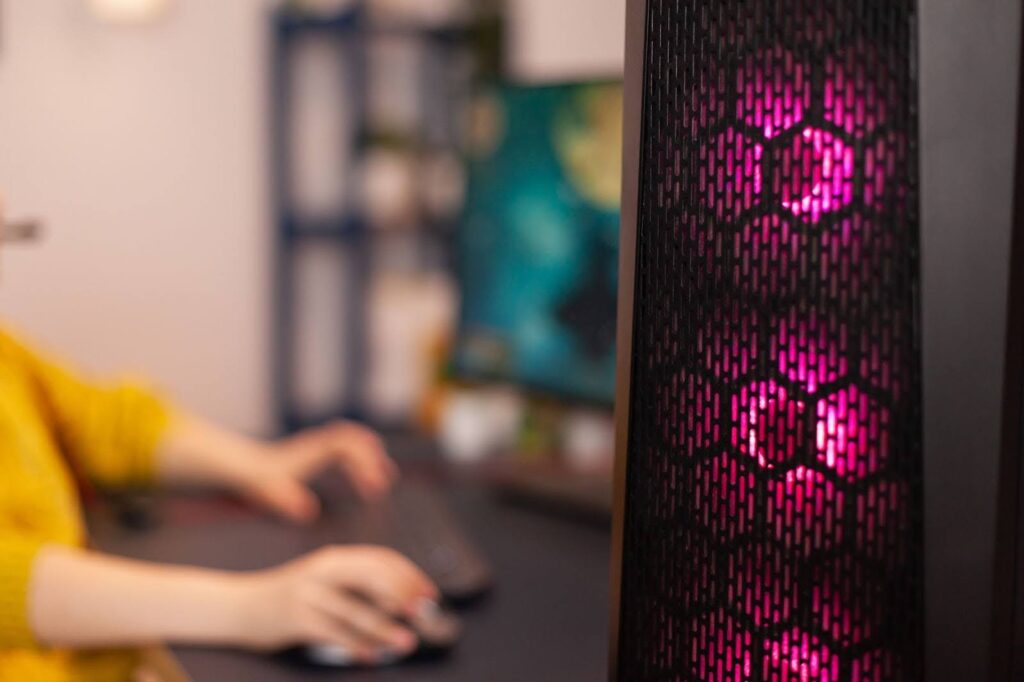 Pessoa realizando manutenção elétrica. Ela usa luvas de proteção vermelhas e brancas e segura um multímetro amarelo conectado a fios elétricos expostos na parede branca, medindo tensão ou continuidade.