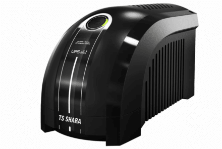 No-break preto da marca TS Shara, com design compacto e arredondado. O equipamento possui acabamento brilhante, indicador luminoso circular na parte frontal e grades laterais de ventilação. A imagem está isolada em fundo branco, destacando o produto.